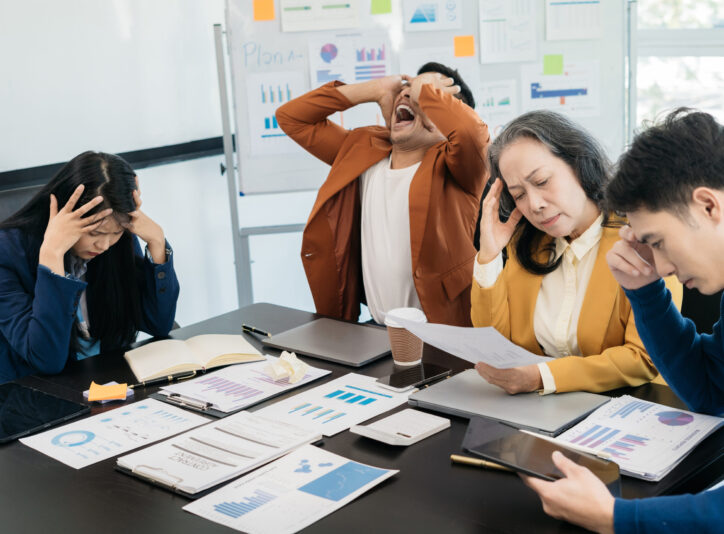 Group of asian business people, teamwork, people and crisis concept - business team sitting sad and solving problems in the office. Failed teamwork concept